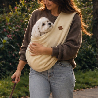 Mujer paseando a su perro mientras lleva otro en el fular de porteo Donna's tela Polar color beige